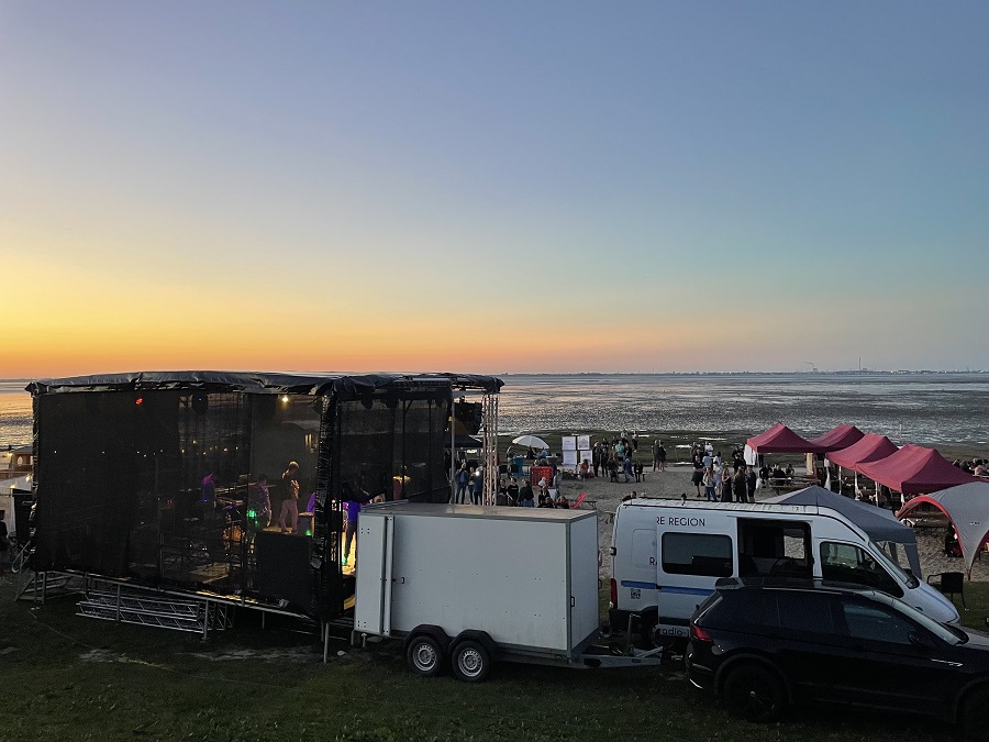 Die BarCamp-Bühne und das Veranstaltungsgelände vor der untergehenden Sonne über dem Wattenmeer.